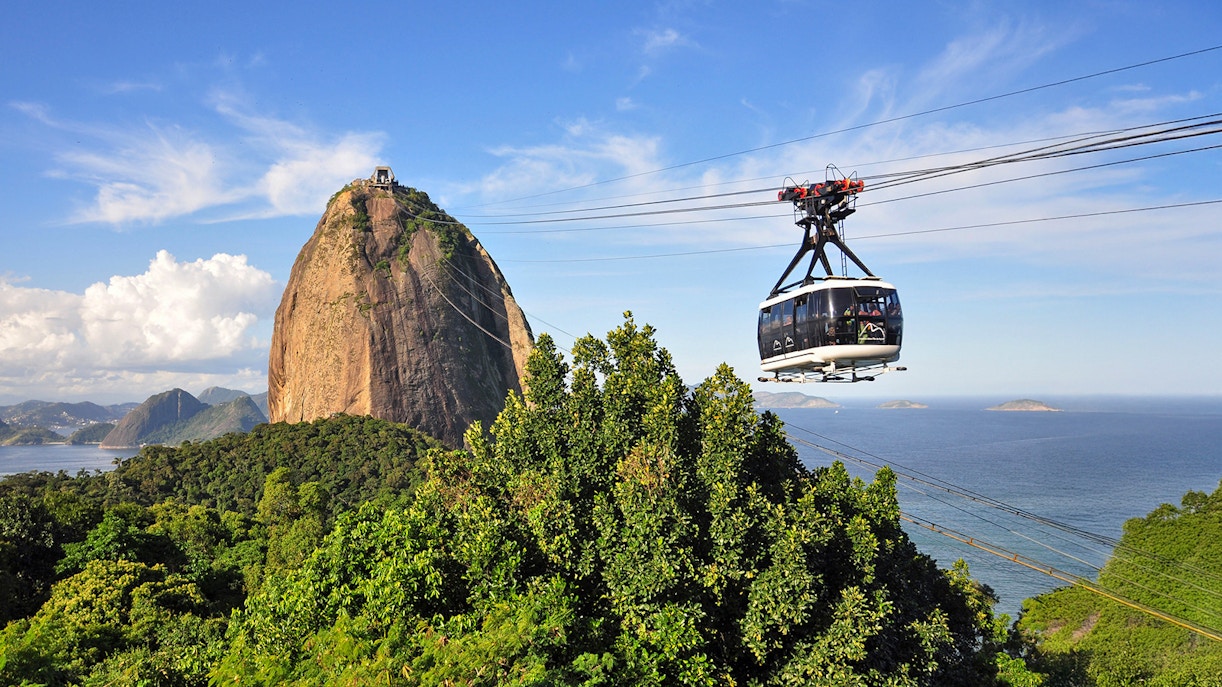 Cable car ascending to Sugarloaf Mountain with panoramic view of Rio de Janeiro.