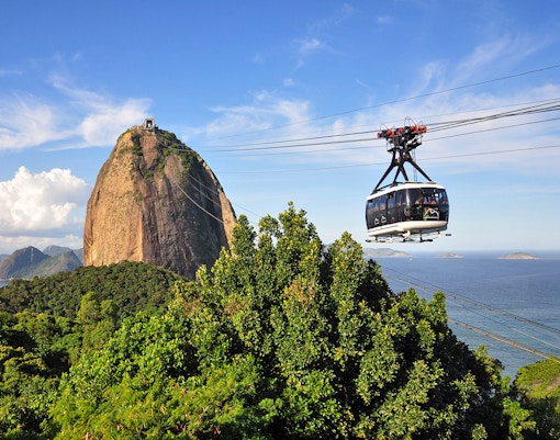 Cable car ascending to Sugarloaf Mountain with panoramic view of Rio de Janeiro.