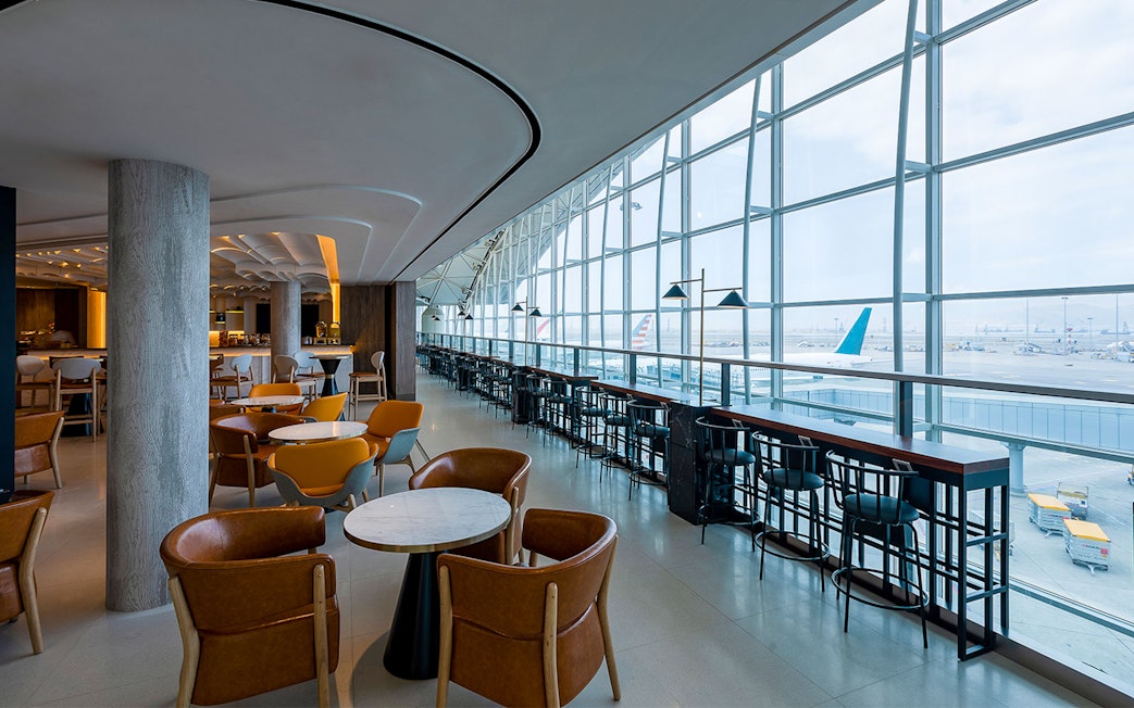 Plaza Premium Lounge with seating and airport runway view through large windows.