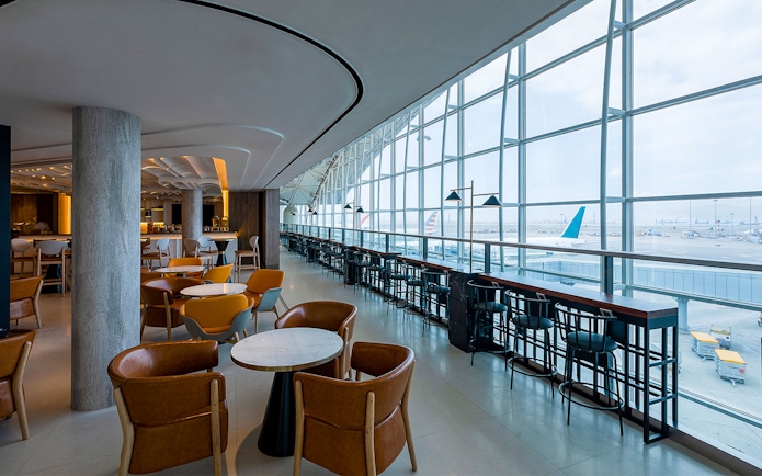 Plaza Premium Lounge with seating and airport runway view through large windows.