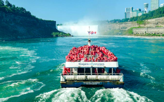 Tour boat approaching Niagara Falls, Canada with passengers in red ponchos.