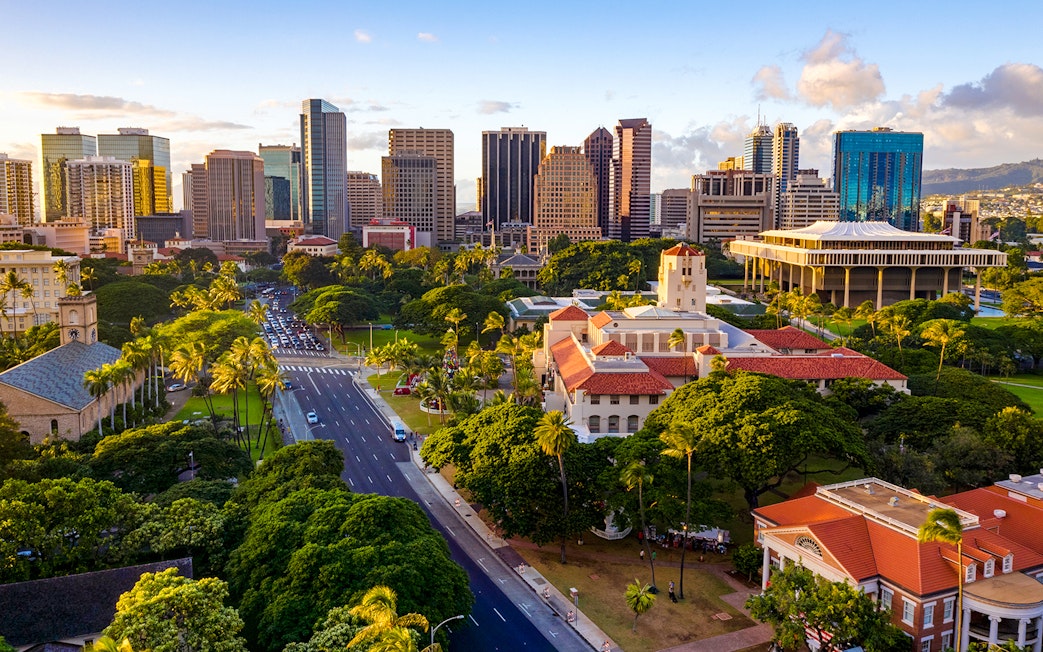 Honolulu Hale with surrounding greenery and Honolulu skyline in the background.