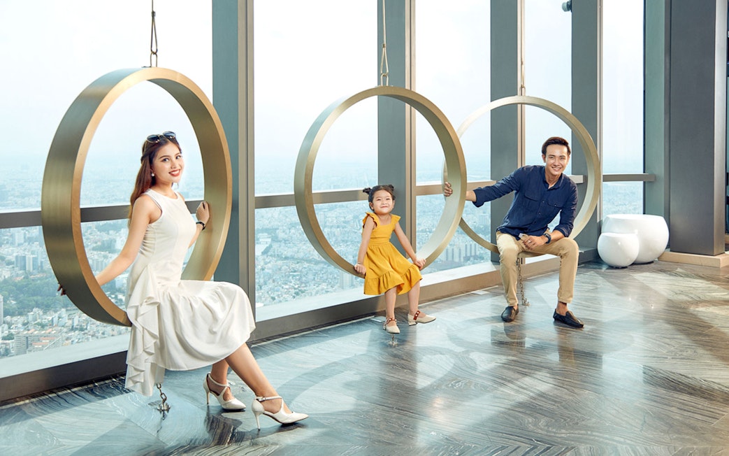 Visitors enjoying circular swings at Saigon Skydeck, Bitexco Financial Tower, with city view.