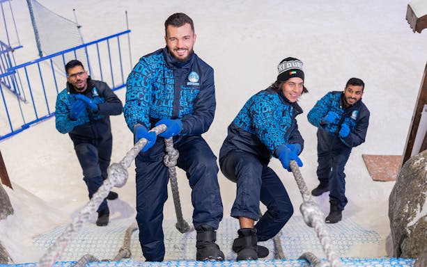 People climbing a rope wall at Ski Dubai Snow Park.