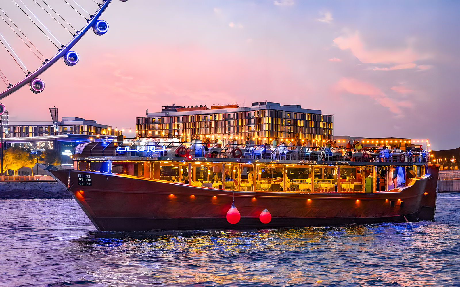 Luxury dhow cruise near Ain Dubai at sunset, with cityscape in the background.