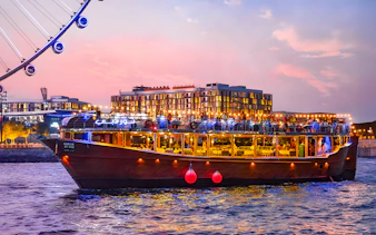 Luxury dhow cruise near Ain Dubai at sunset, with cityscape in the background.