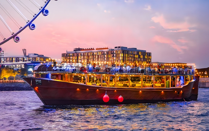 Luxury dhow cruise near Ain Dubai at sunset, with cityscape in the background.