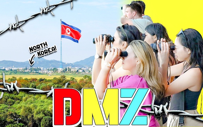 Tour group at DMZ observatory using binoculars to view North Korean village and flag.