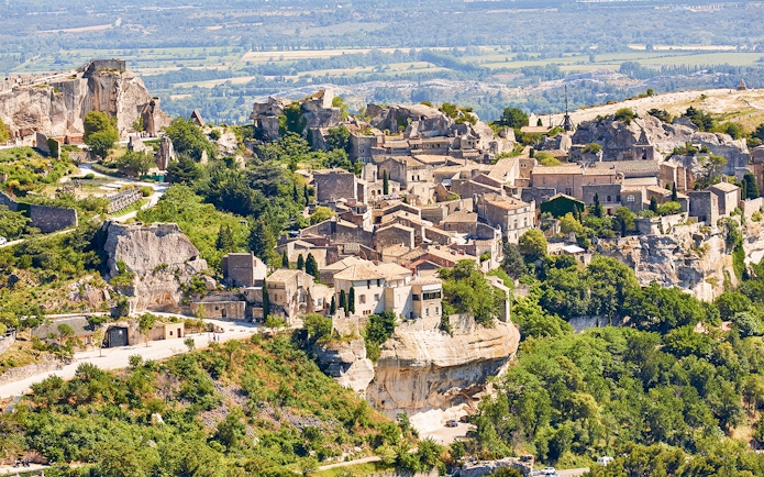 Hilltop village of Les Baux-de-Provence with stone buildings and lush greenery, Provence tour.