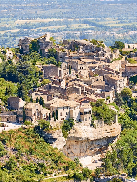 Hilltop village of Les Baux-de-Provence with stone buildings and lush greenery, Provence tour.