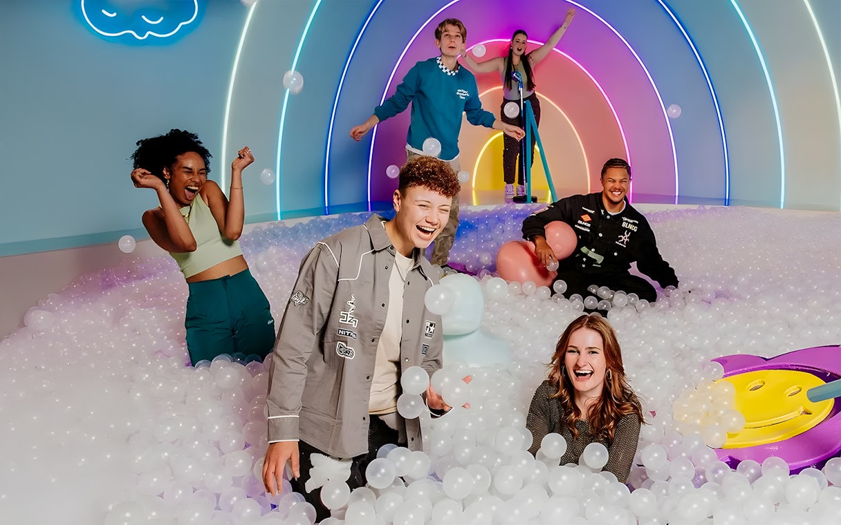 Visitors enjoying The Pool Upside Down Amsterdam with colorful lights and ball pit.