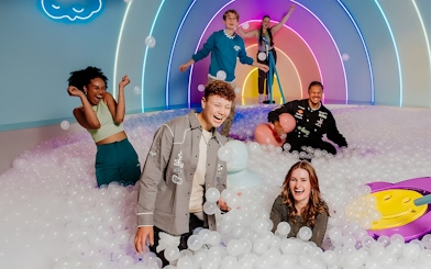 Visitors enjoying The Pool Upside Down Amsterdam with colorful lights and ball pit.