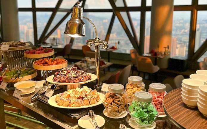Buffet spread at ORBIT Revolving Restaurant in KL Tower with city view.