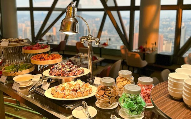 Buffet spread at ORBIT Revolving Restaurant in KL Tower with city view.