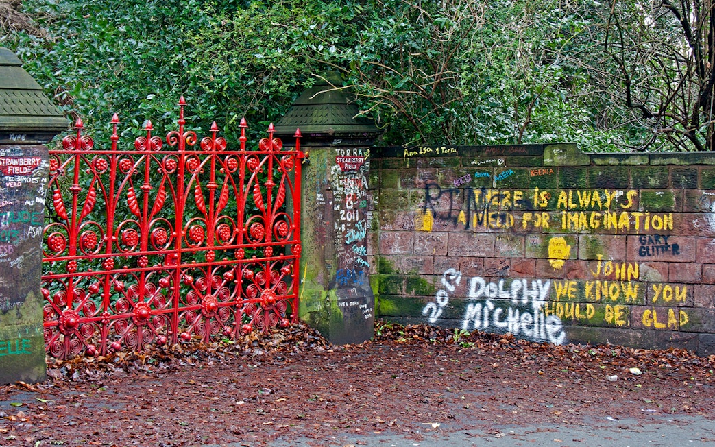 Strawberry Field Gates in Liverpool with graffiti-covered brick wall.