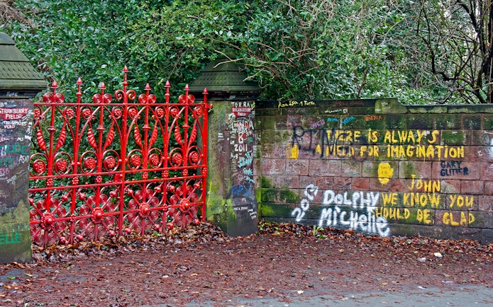 Strawberry Field Gates in Liverpool with graffiti-covered brick wall.