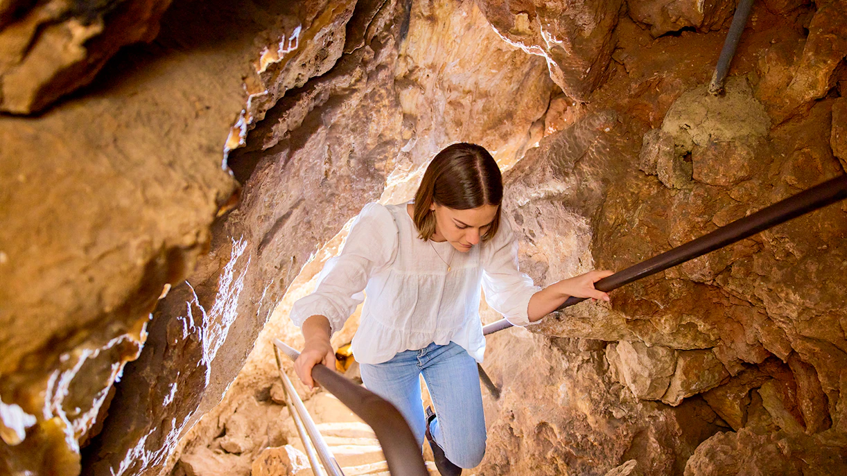 Tourist climbing up the stairs inside cave