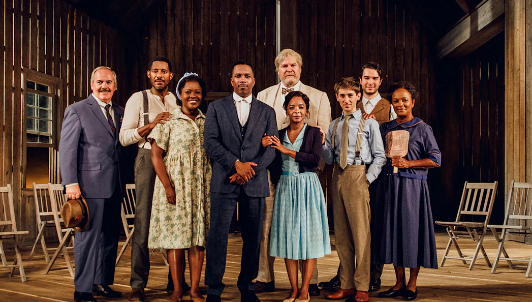 Cast of "Purlie Victorious" standing on a wooden stage in period costumes.