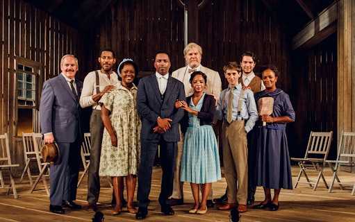 Cast of "Purlie Victorious" standing on a wooden stage in period costumes.