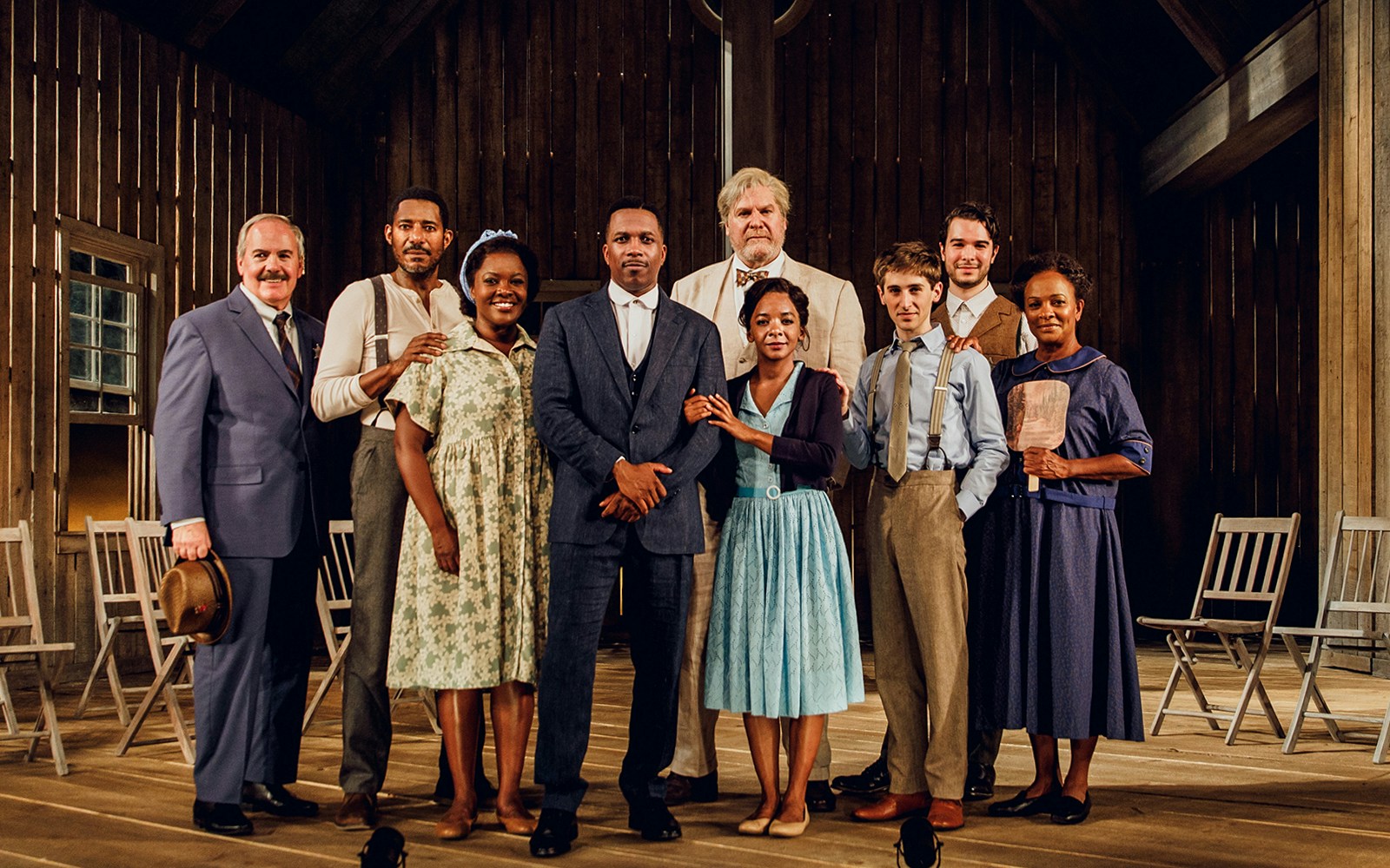 Cast of "Purlie Victorious" standing on a wooden stage in period costumes.