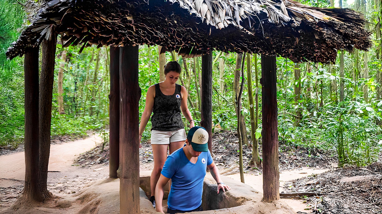 Visitors entering Cu Chi tunnel with guide in Ho Chi Minh City, Vietnam.