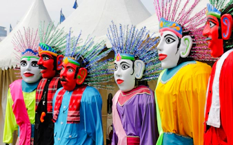 Ondel-ondel figures in colorful attire at a cultural festival in Jakarta.