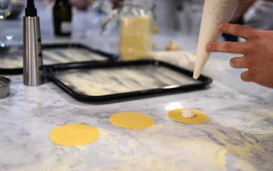 Piping filling onto pasta circles during Milan cooking class.