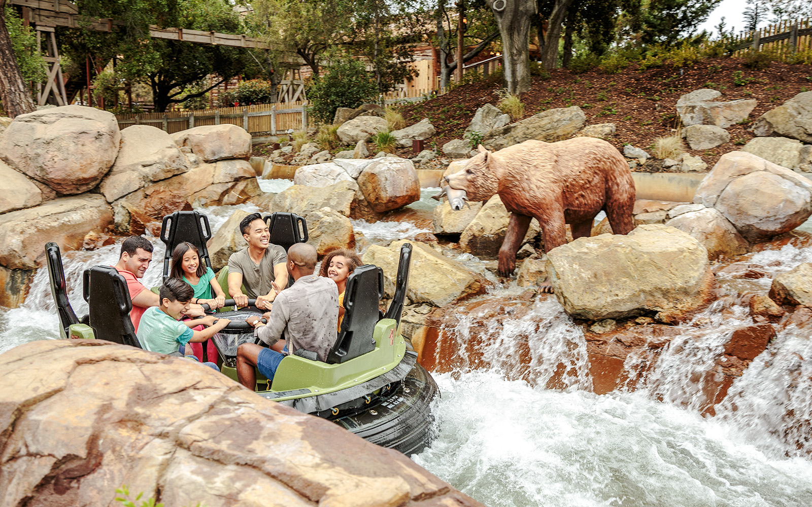 Rafting adventure on Calico River Rapids at Knott's Berry Farm with bear statue nearby.