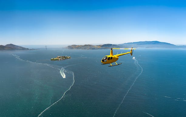 Helicopter flying near Alcatraz Island with Golden Gate Bridge in the background, San Francisco tour.