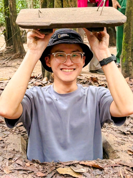 Tourist emerging from Cu Chi tunnel entrance in Vietnam.