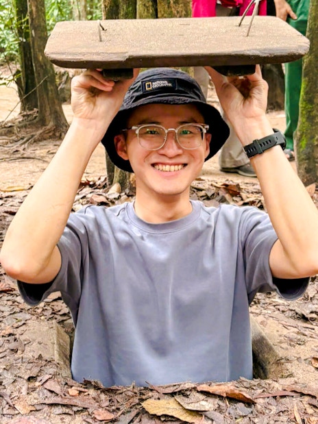 Tourist emerging from Cu Chi tunnel entrance in Vietnam.