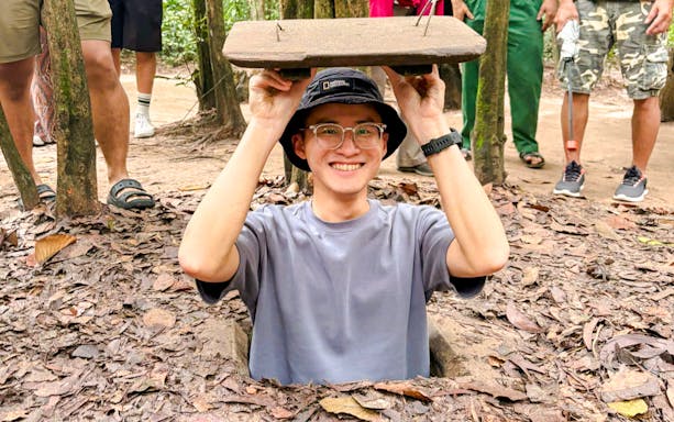Tourist emerging from Cu Chi tunnel entrance in Vietnam.
