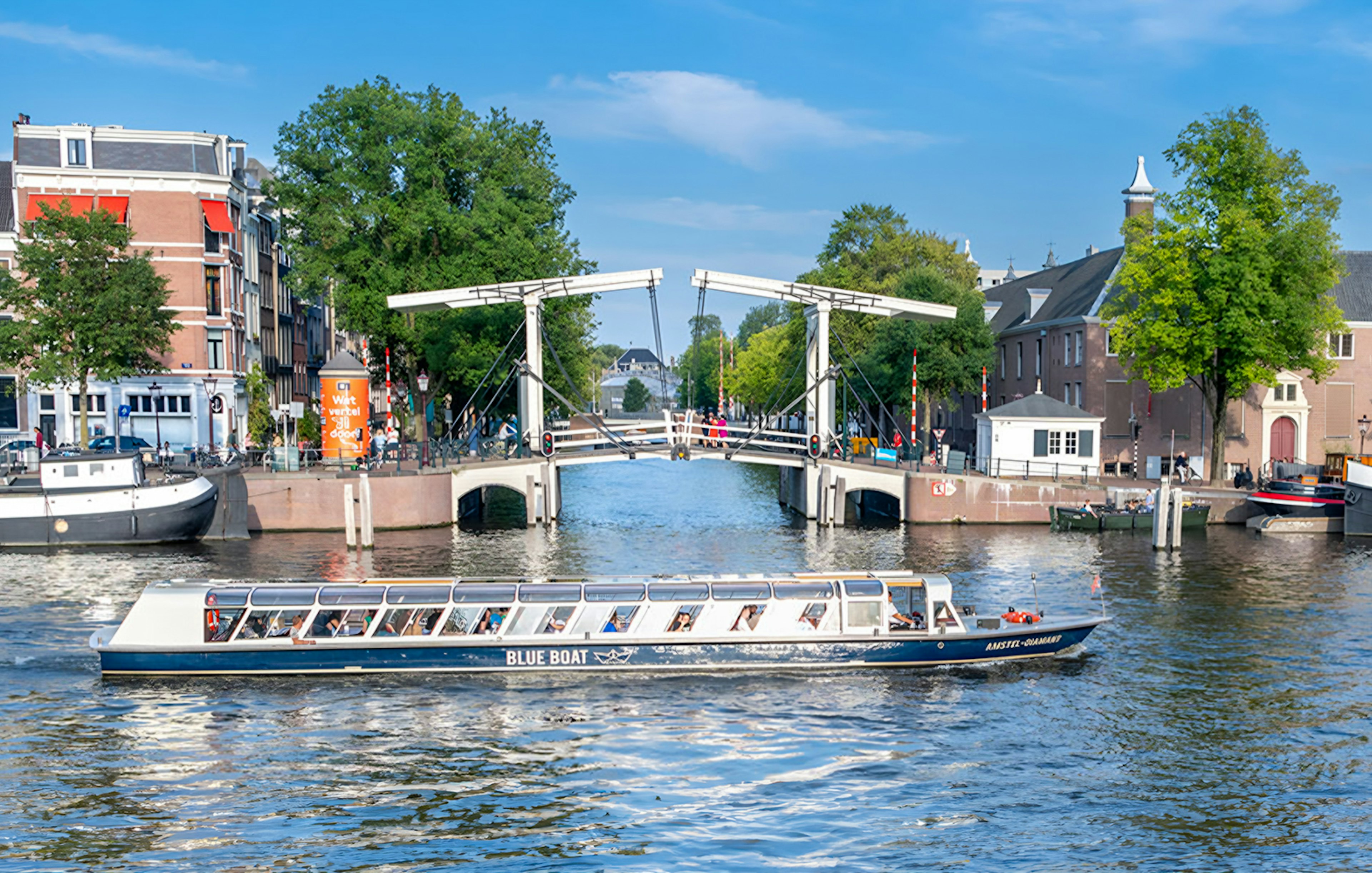 Canal cruise boat passing under the Skinny Bridge in Amsterdam.