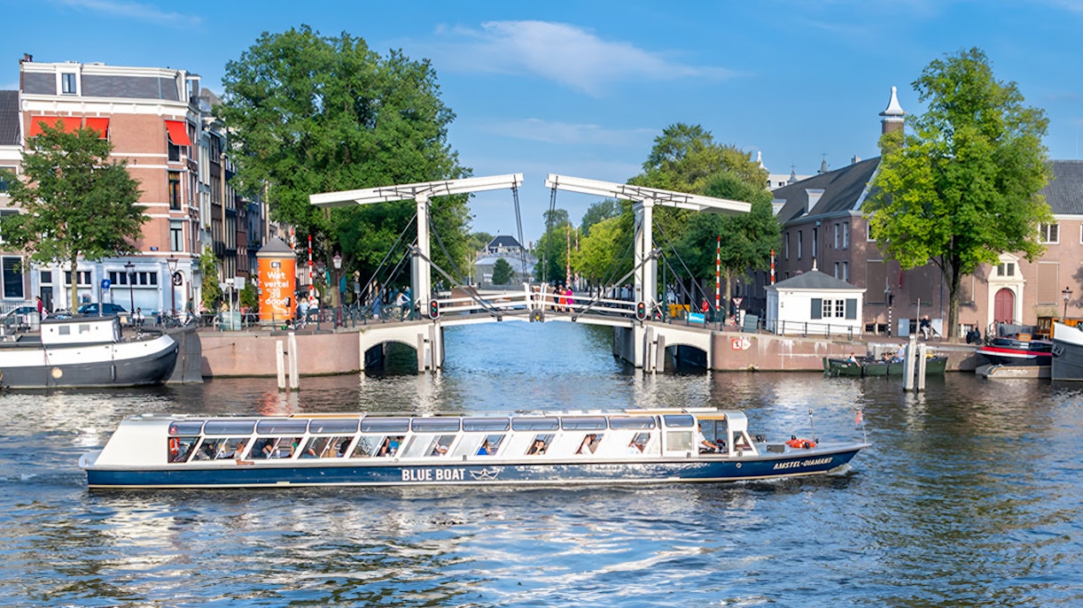 Canal cruise boat passing under the Skinny Bridge in Amsterdam.
