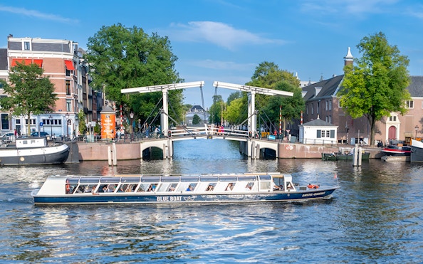 Canal cruise boat passing under the Skinny Bridge in Amsterdam.