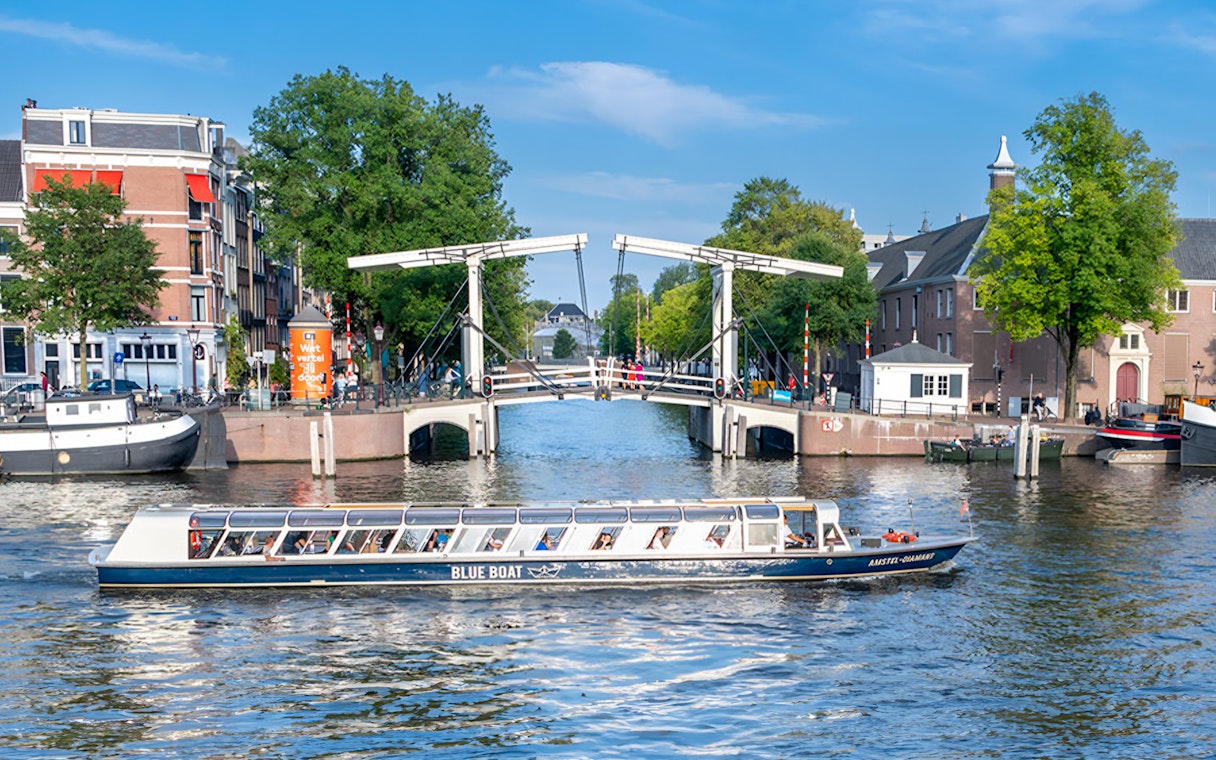 Canal cruise boat passing under the Skinny Bridge in Amsterdam.