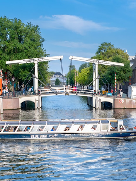 Canal cruise boat passing under the Skinny Bridge in Amsterdam.