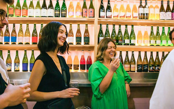 Visitors enjoying drinks at a wine stall in Borough Market, London.