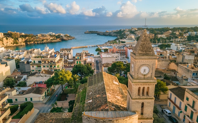 Panoramic view of Porto Cristo with a clock tower and harbor on Mallorca's east coast, Spain.