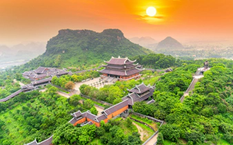 Bai Dinh temple complex at sunset, surrounded by lush greenery in Ninh Binh, Vietnam.