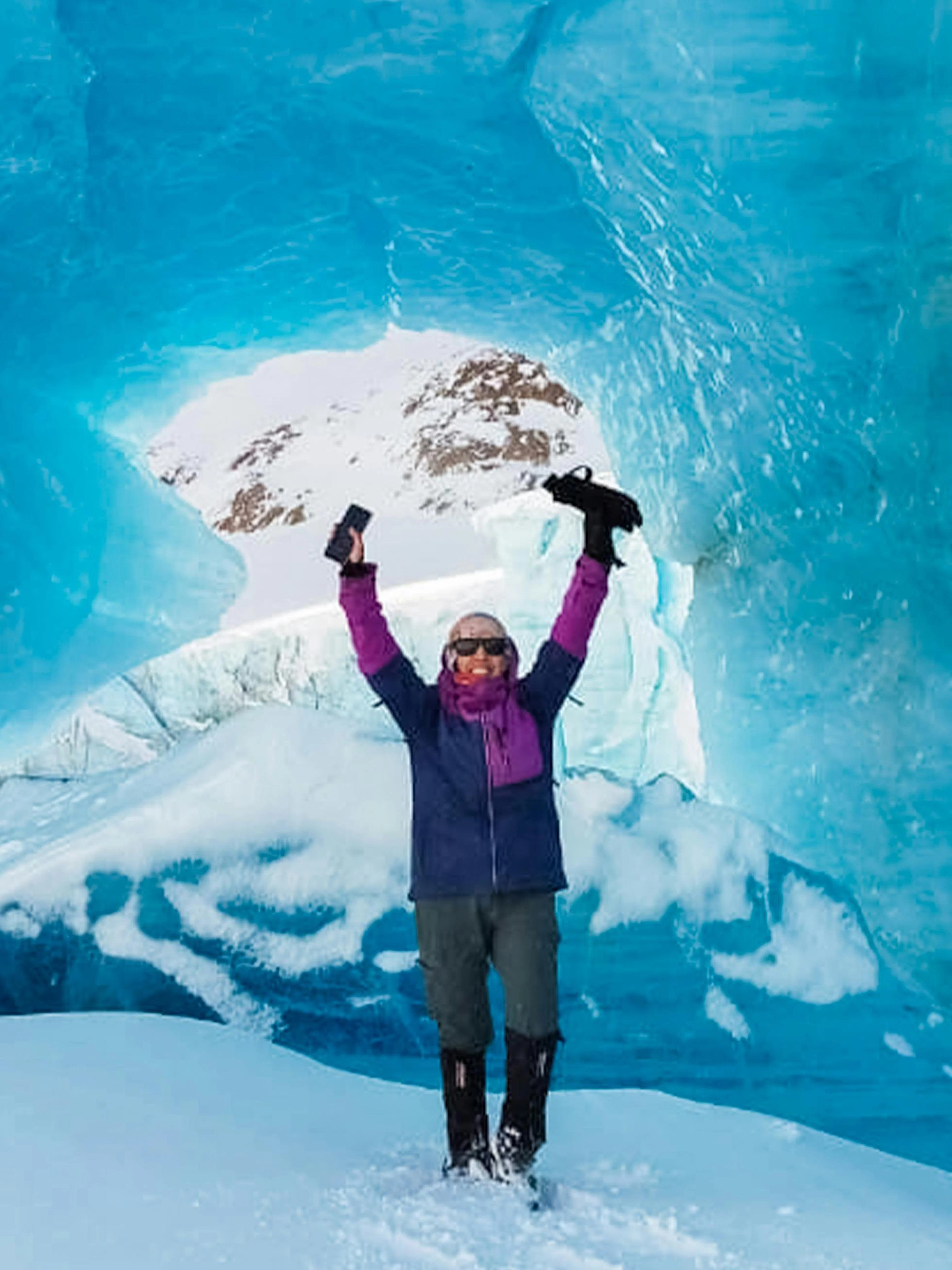 Trekker celebrating inside ice cave on Ojo del Albino Glacier, Argentina.