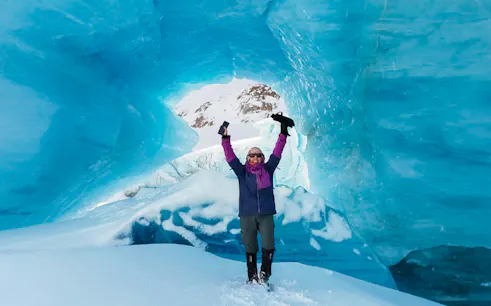 Trekker celebrating inside ice cave on Ojo del Albino Glacier, Argentina.