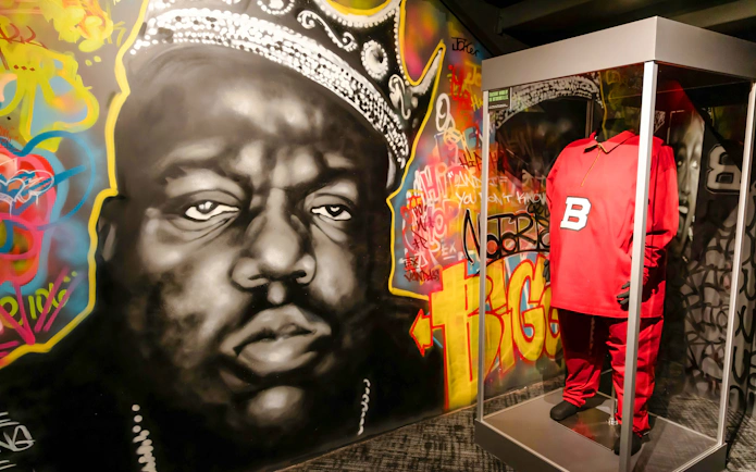 Graffiti mural and red outfit display at Biggie exhibit inside RiseNY.