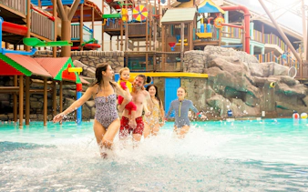 Family enjoying the pool at Alton Towers Waterpark with colorful slides in the background.