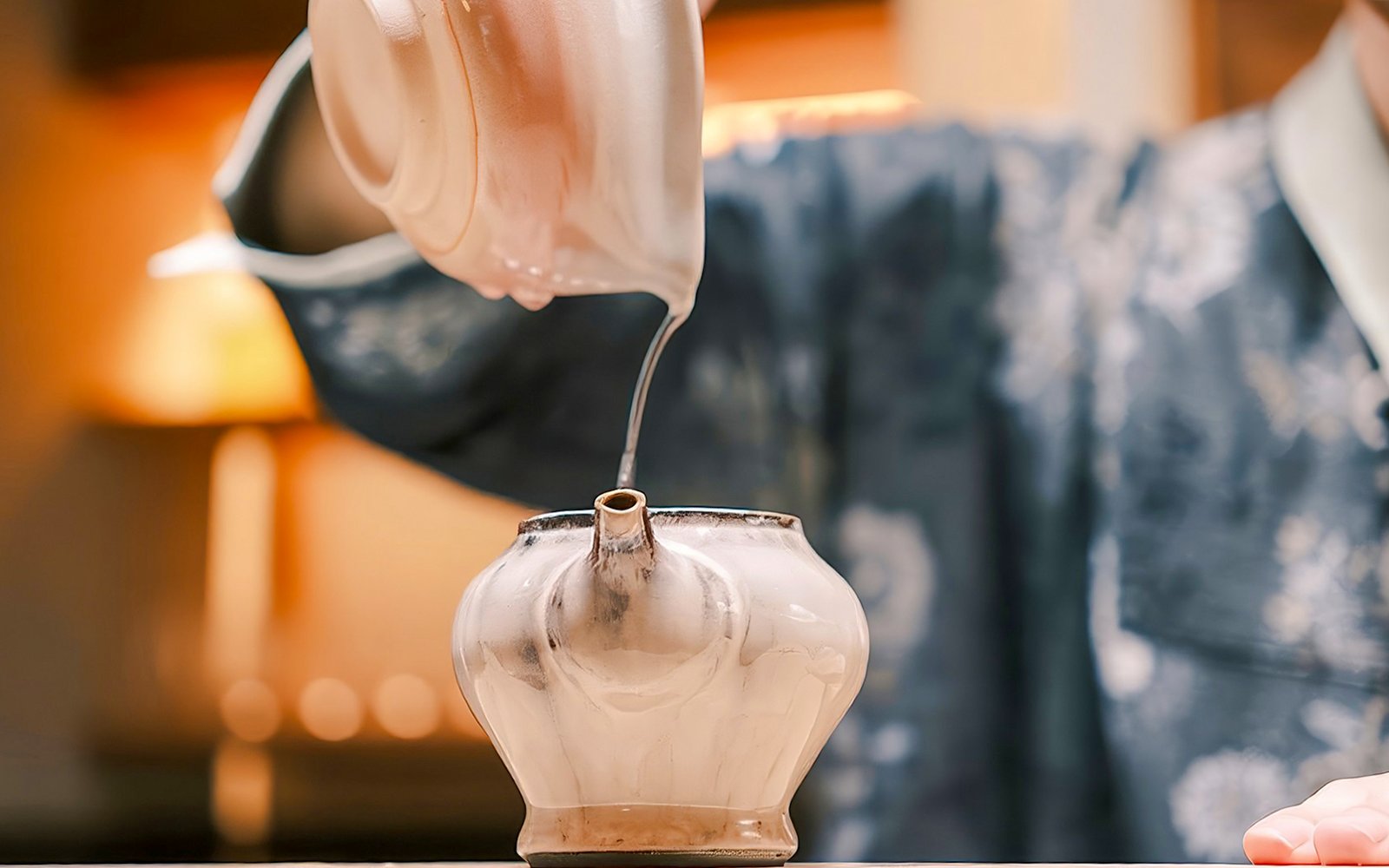 Pouring hot tea into a traditional pot during a private tea ceremony.