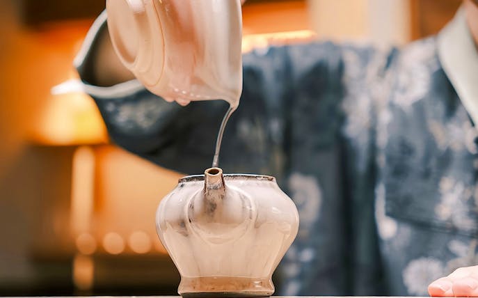 Pouring hot tea into a traditional pot during a private tea ceremony.