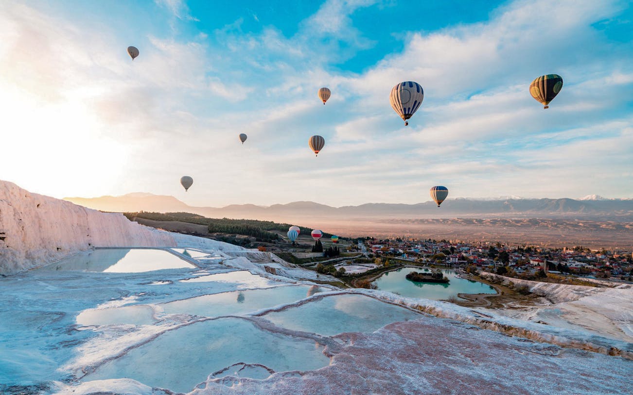 Hot air balloons over Pamukkale's travertine terraces, Antalya day trip.
