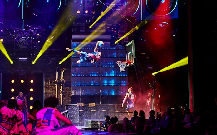 Performer dunking basketball during Mad Apple show in New York City theater.