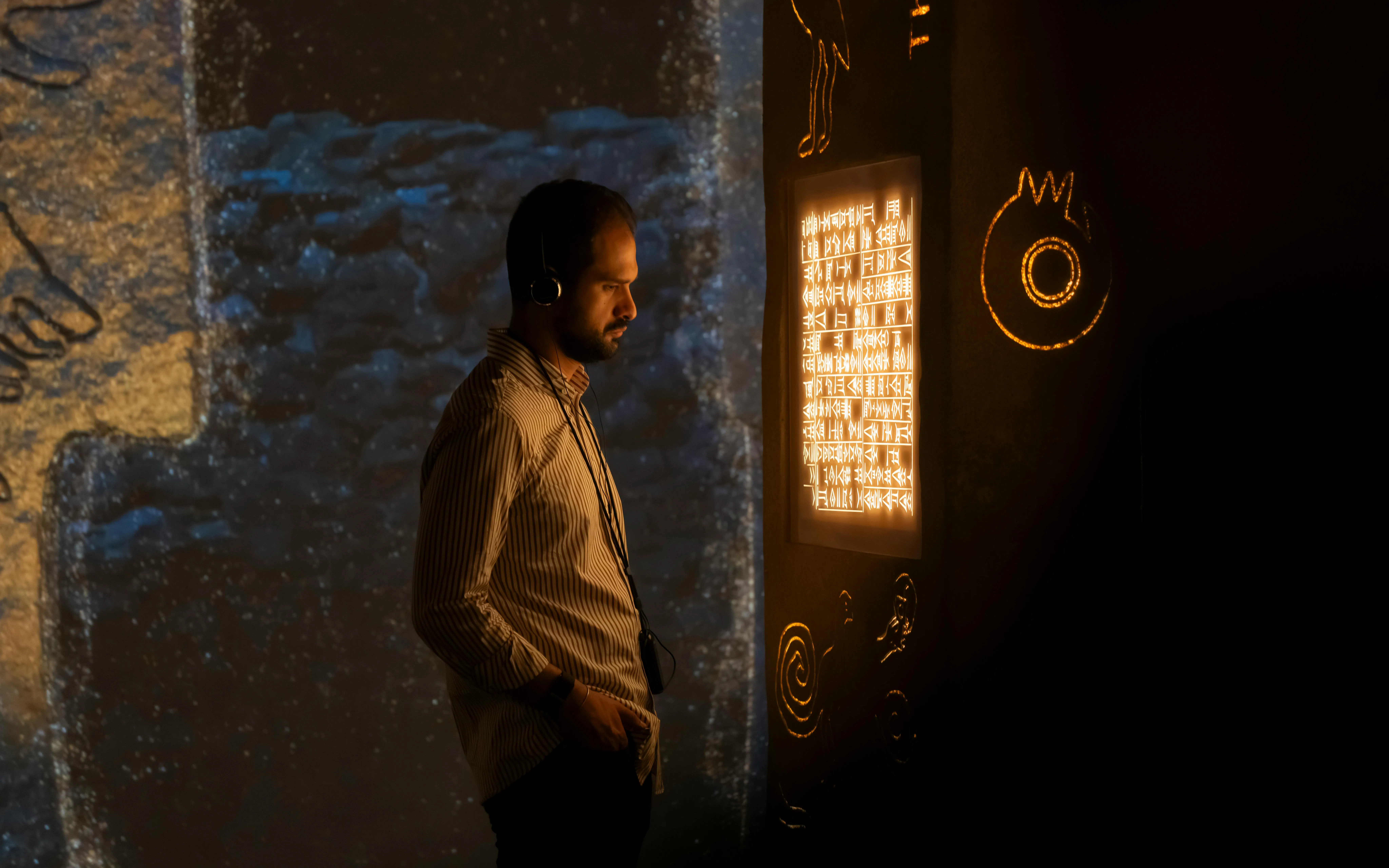 Man observing illuminated ancient script at London Timewalk Exhibition.