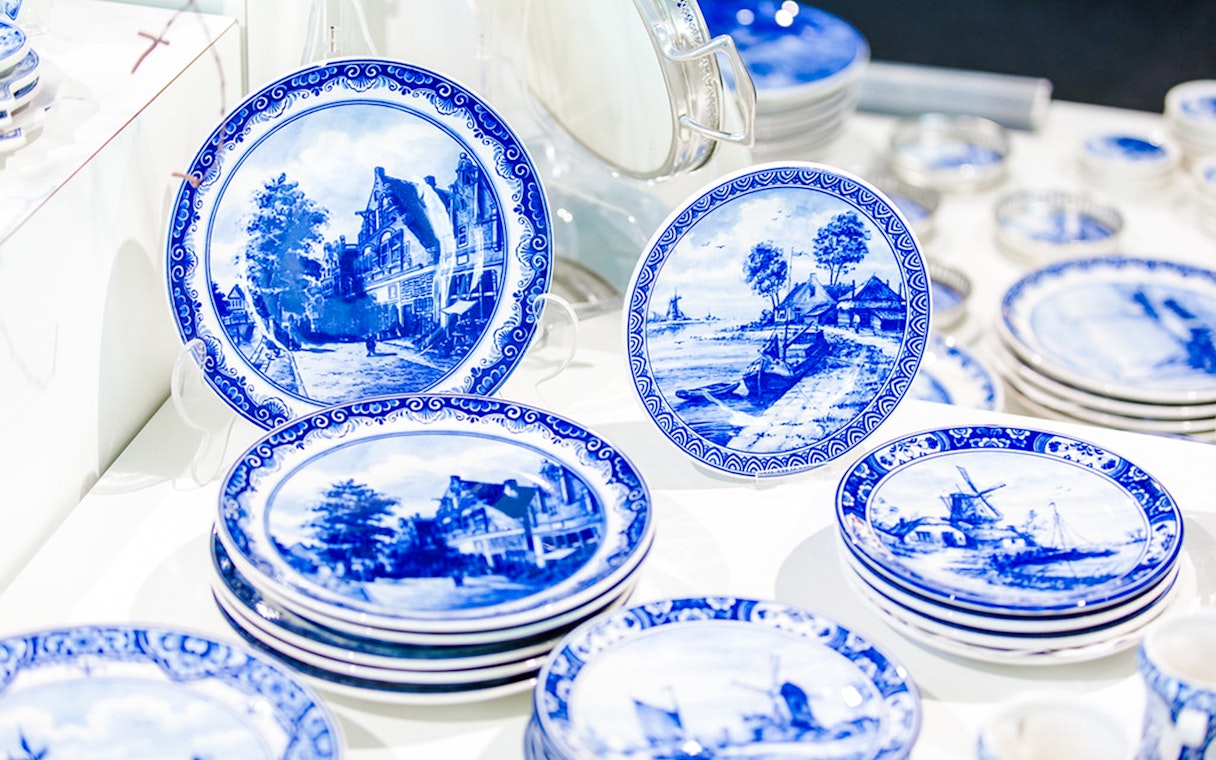 Royal Delft Blue pottery plates with scenic designs on display.